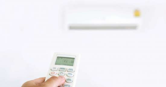 Women using remote control on the conditioner in home